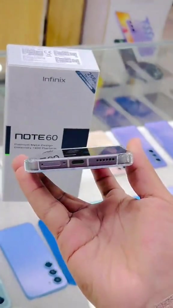 Kotak Infinix NOTE 60 dengan tulisan Premium Metal Design, Dimensity 7400 Platform dan phone berbumbung lutsinar dilihat dari bahagian bawah