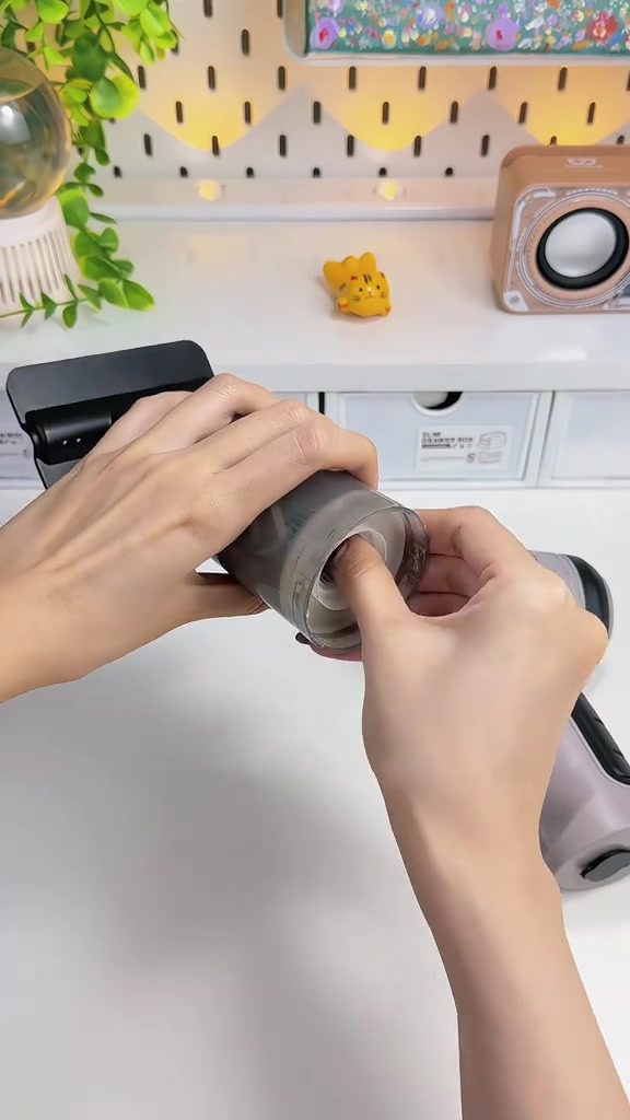 Hai tay đang tháo cốc bụi nhựa đục và lõi lọc khỏi thân máy hút bụi cầm tay