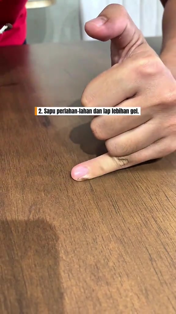 Jari menyapu gel kayu coklat pada permukaan meja kayu ikut arah urat kayu