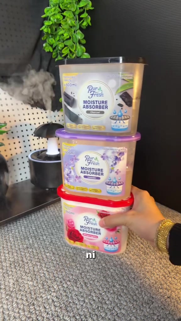Tiga bekas Pure Fresh Moisture Absorber 600ml perisa charcoal, lavender dan rose dipegang bertindan