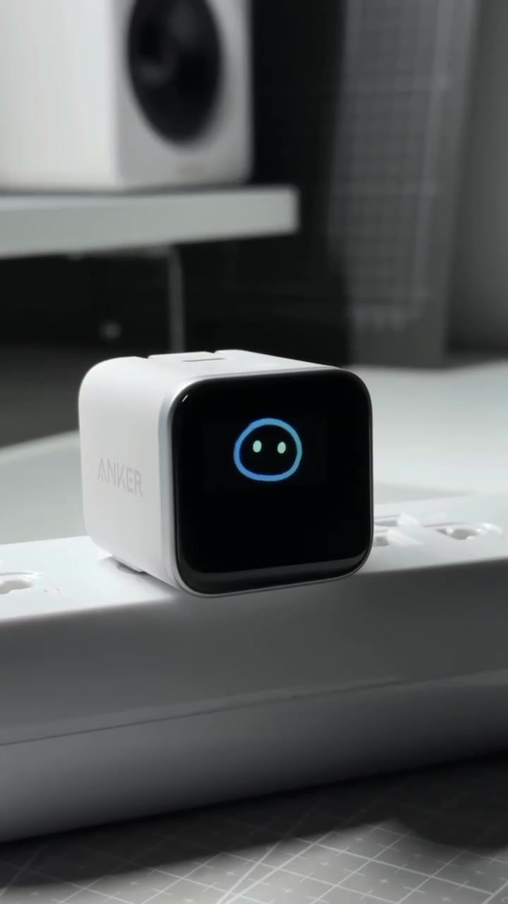 Pengecas Anker Nano 45W Smart Display warna putih atas power strip dengan skrin menunjukkan muka senyum biru