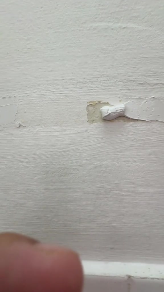 Tompok paste putih atas kawasan cat yang terkopek pada dinding putih