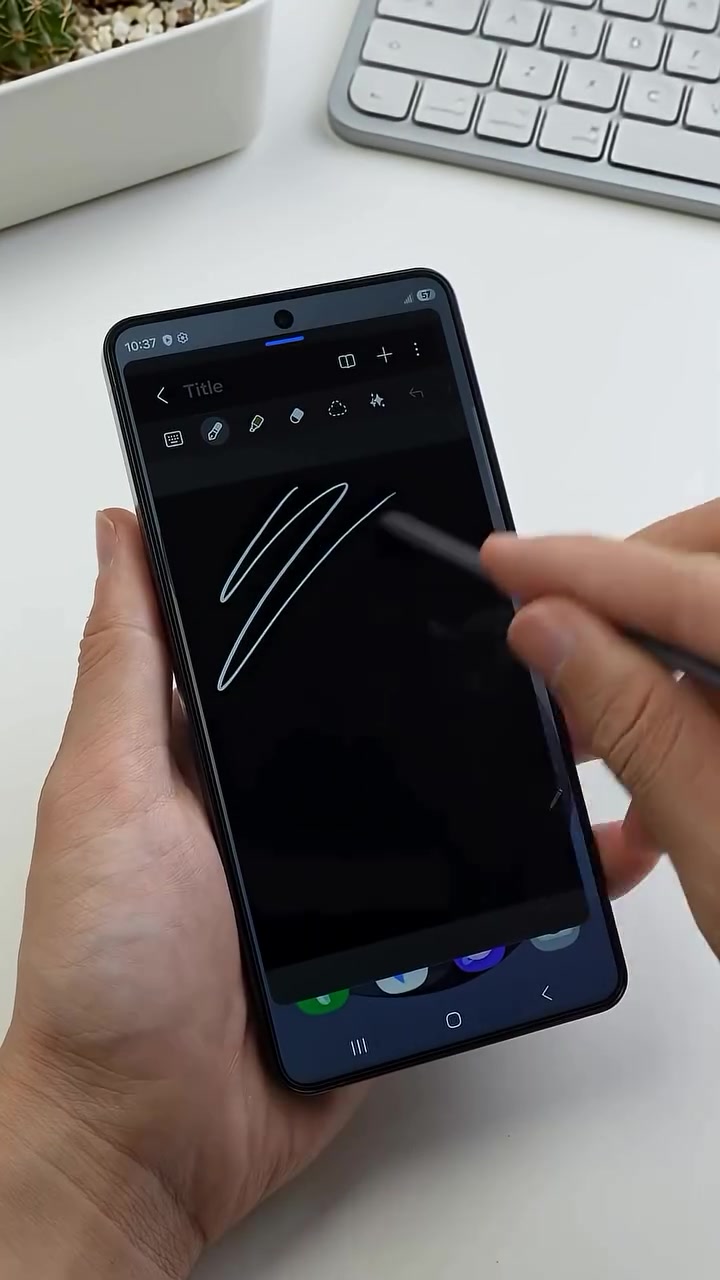 Galaxy S26 Ultra dipegang satu tangan sambil S Pen menulis garisan putih pada skrin nota