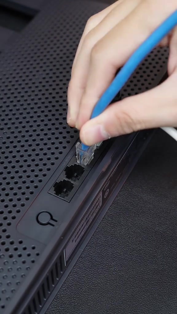 Bàn tay cắm đầu dây LAN màu xanh vào cụm cổng mạng phía sau router màu đen