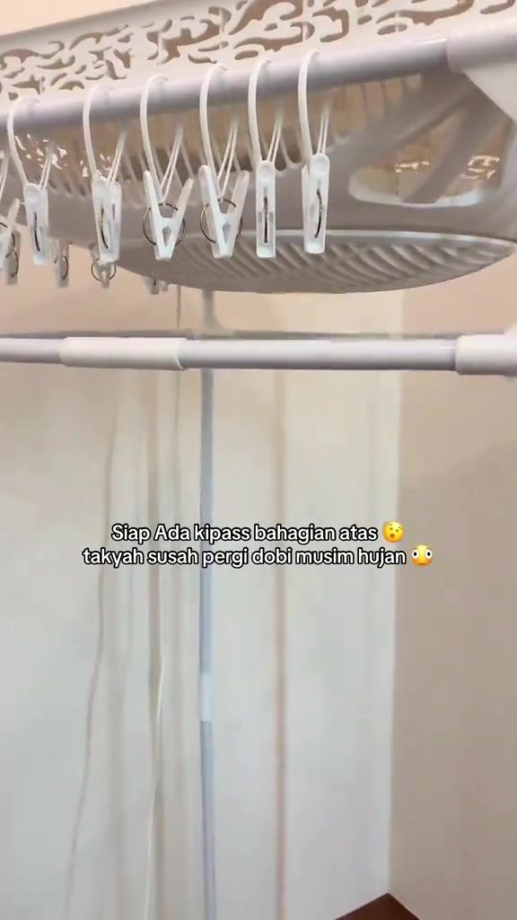 Bahagian bawah unit rak siling berpemanas dengan kipas bulat dan barisan klip baju putih, dilihat dari bawah