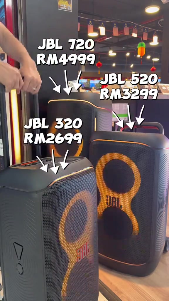 Dua speaker JBL PartyBox dengan gelang lampu oren di rak kedai, berlabel JBL 720 RM4,999, JBL 520 RM3,299 dan JBL 320 RM2,699