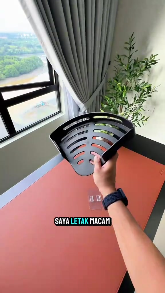 Tangan memegang rak sudut hitam berlubang dengan patch pelekat jernih di atas meja