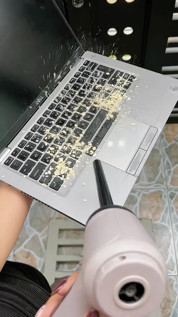 Đầu vòi máy hút bụi cầm tay thổi bung vụn bẩn khỏi bàn phím laptop