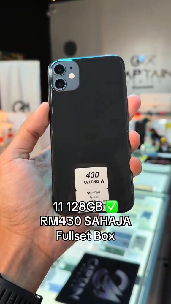 iPhone 11 hitam di tangan dengan pelekat putih bertulis 430 LELONG di hadapan logo kedai Captain Mobile