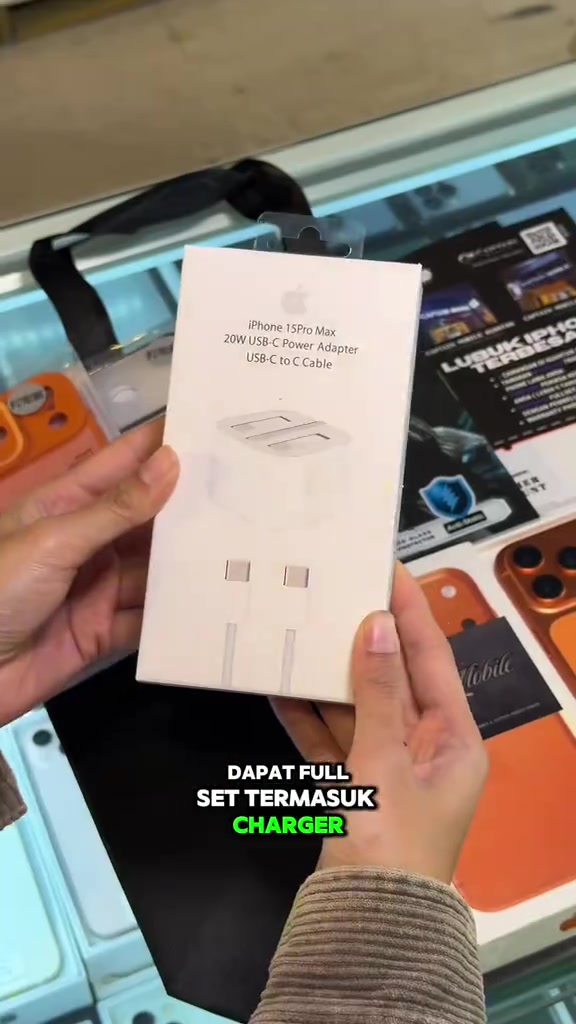 Kotak adapter 20W USB-C Power Adapter dengan kabel USB-C ke USB-C dipegang di kaunter kedai sebagai sebahagian full set
