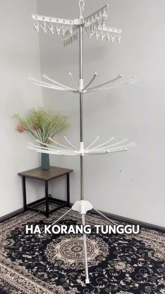 组装完成的白色三层晾衣架,顶层为夹子层,立在室内墙角