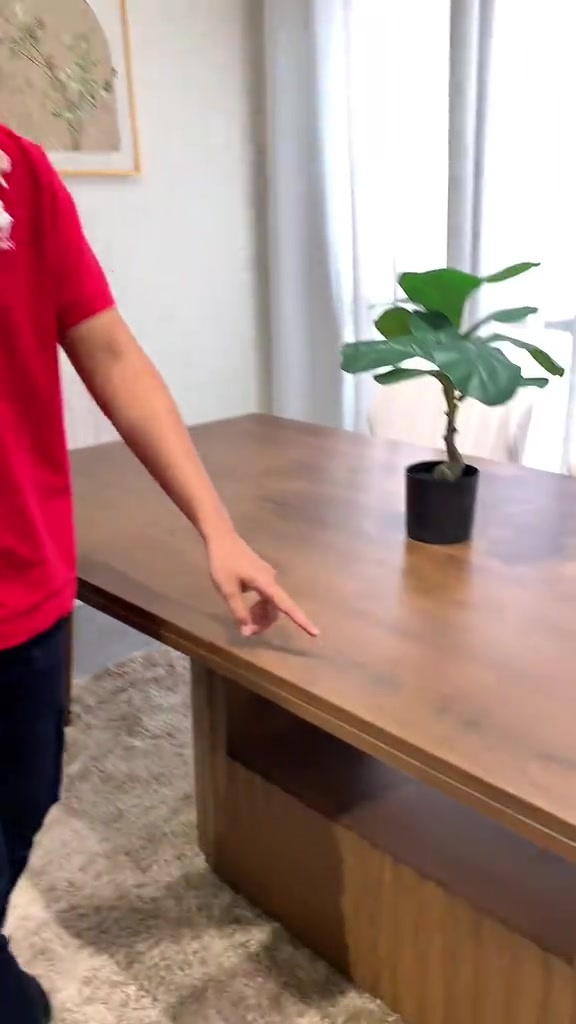 Tangan menunjuk kesan putih samar pada permukaan meja kayu coklat