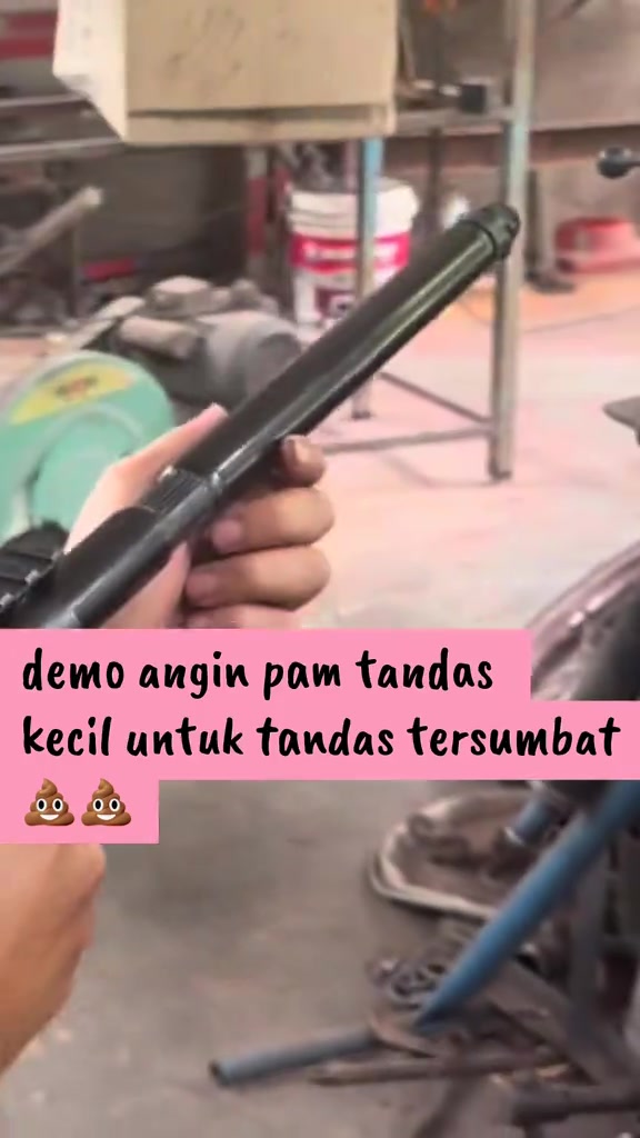 Tangan memegang batang pam angin tandas warna hitam dengan hujung muncung