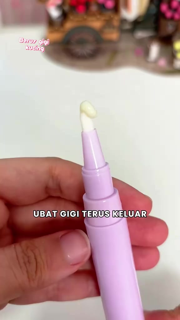 Tangan memegang berus gigi kecil untuk kucing dengan sedikit pes pada hujungnya