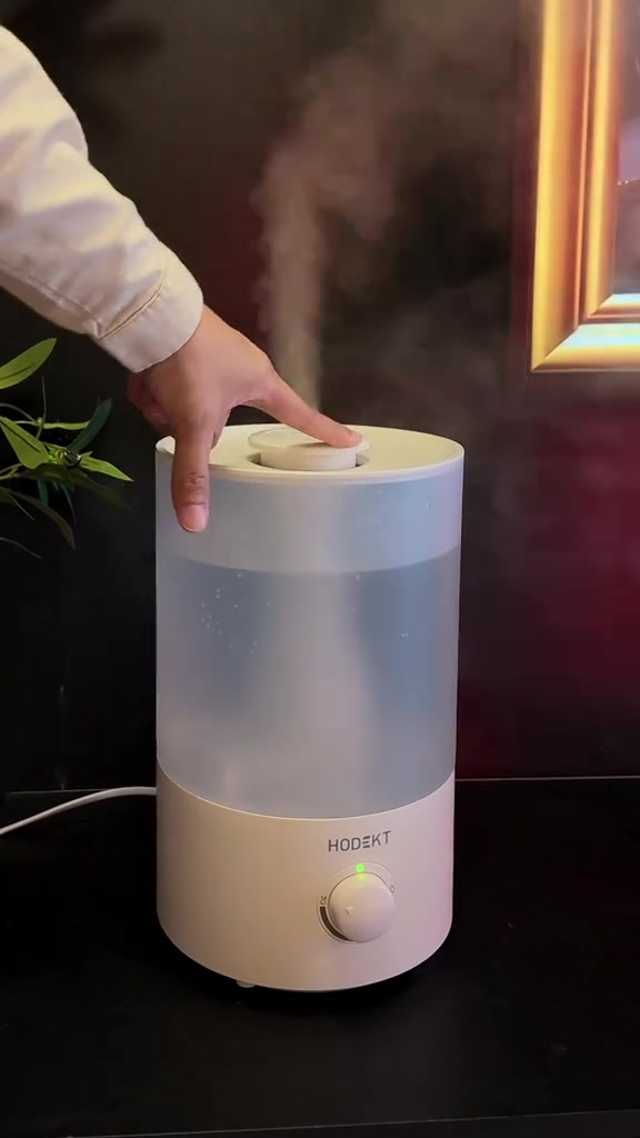 Tangan mengendalikan humidifier silinder di atas meja, tanpa wajah kelihatan
