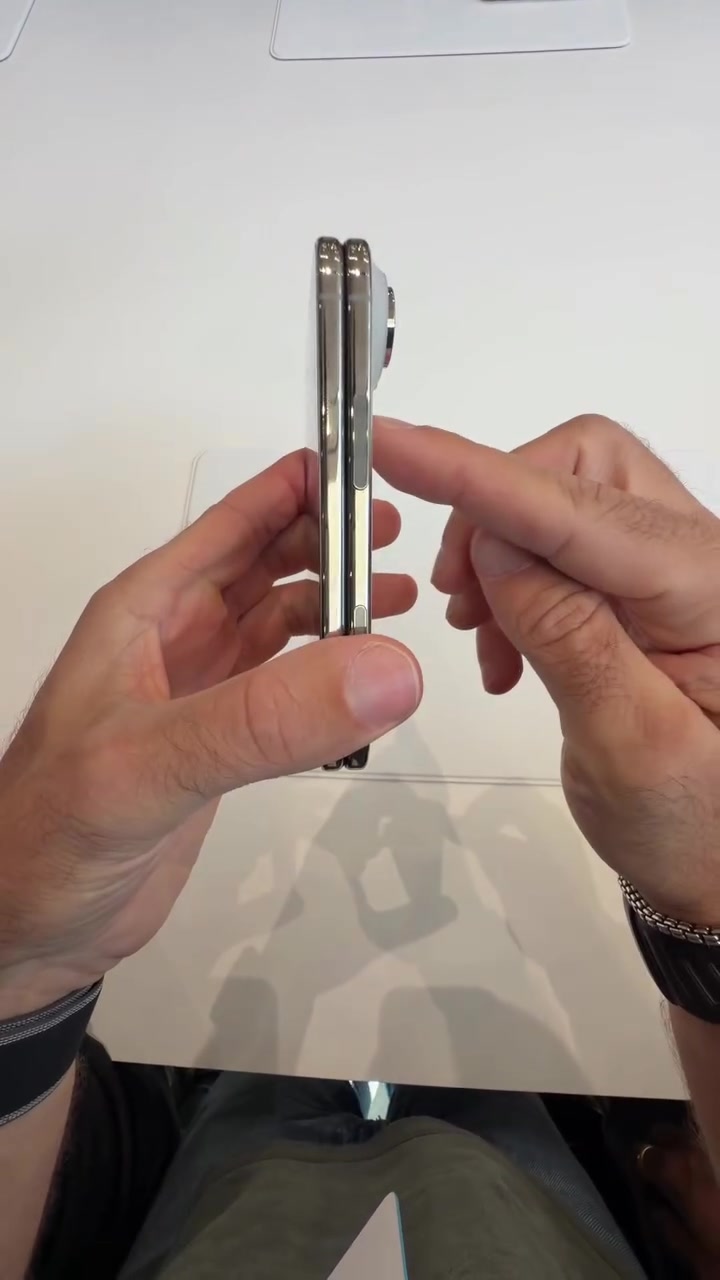 Telefon lipat dipegang dari arah tepi, memperlihatkan sisi yang nipis.