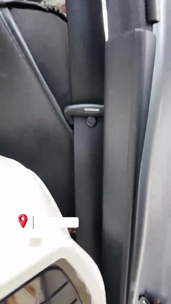 Carrier putih diletak berhampiran tali keledar di tempat duduk belakang kereta