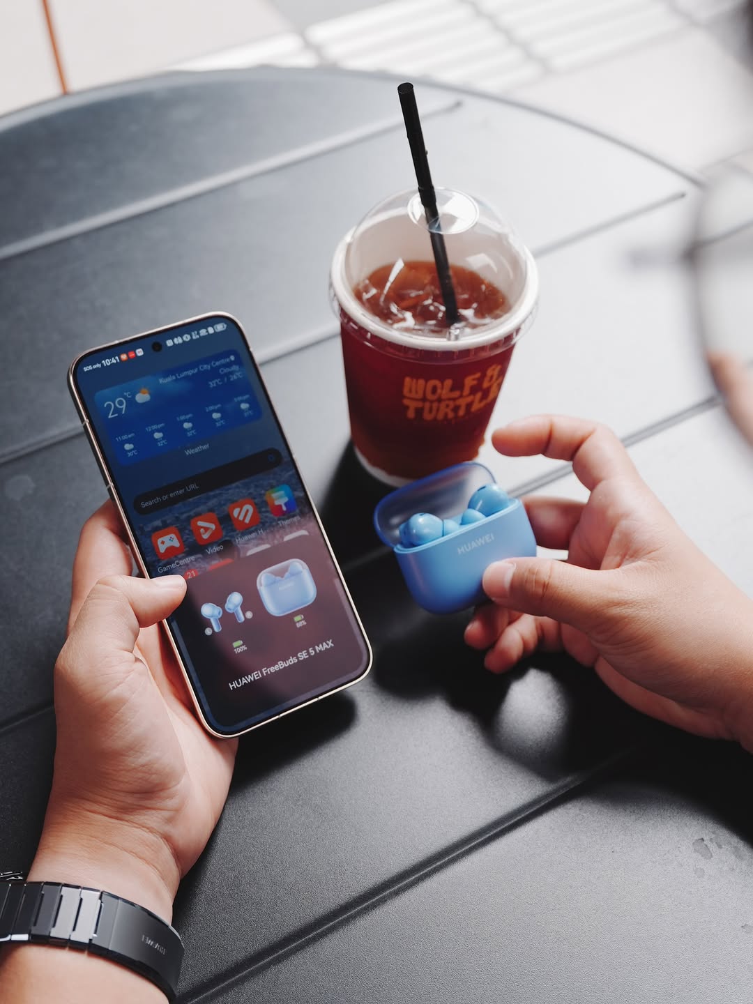 Telefon pintar memaparkan notifikasi sambungan HUAWEI FreeBuds SE 5 MAX di sebelah bekas pengecas biru terbuka atas meja