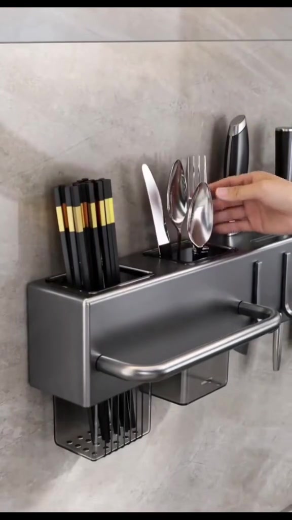 Tangan memasukkan sudu ke dalam rak dapur hitam yang dipasang pada dinding