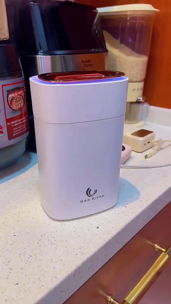 Humidifier silinder diletakkan di atas meja bersama barangan rumah di latar belakang