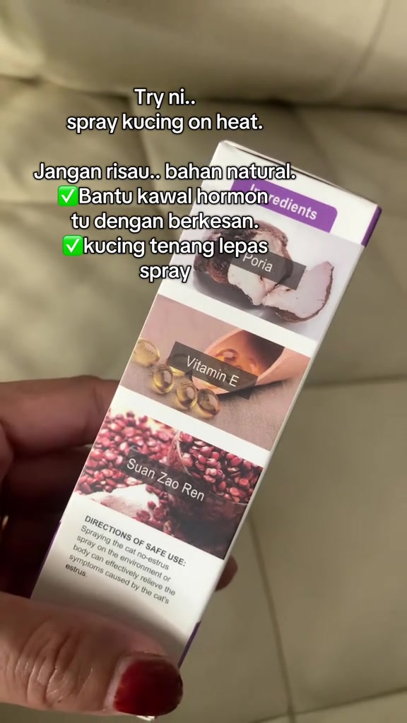 Tangan memegang kotak produk semburan kucing on heat dengan senarai bahan seperti poria, vitamin E dan suan zao ren