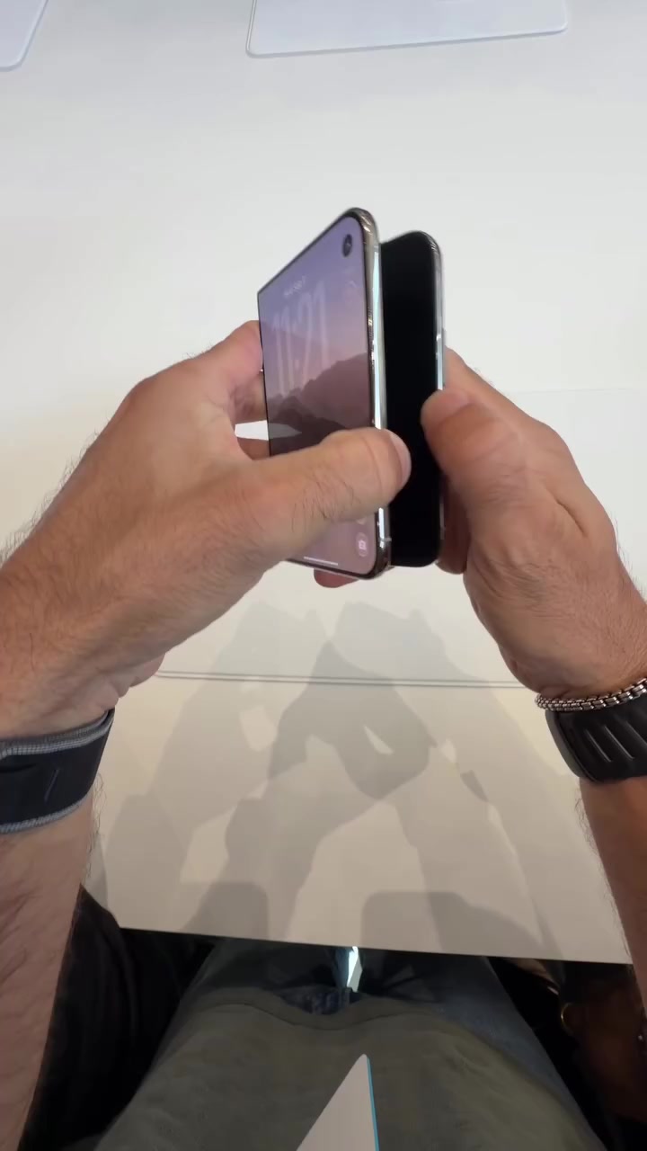 Telefon lipat sedang dibuka separuh dan dipegang dengan dua tangan.