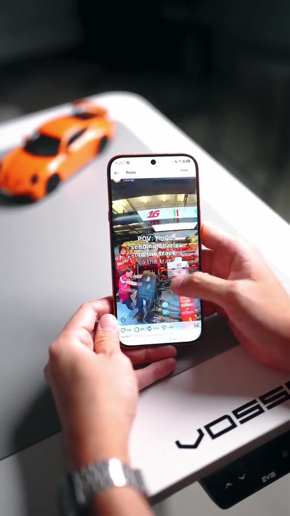 Telefon memaparkan feed media sosial pada skrin semasa dipegang dengan dua tangan