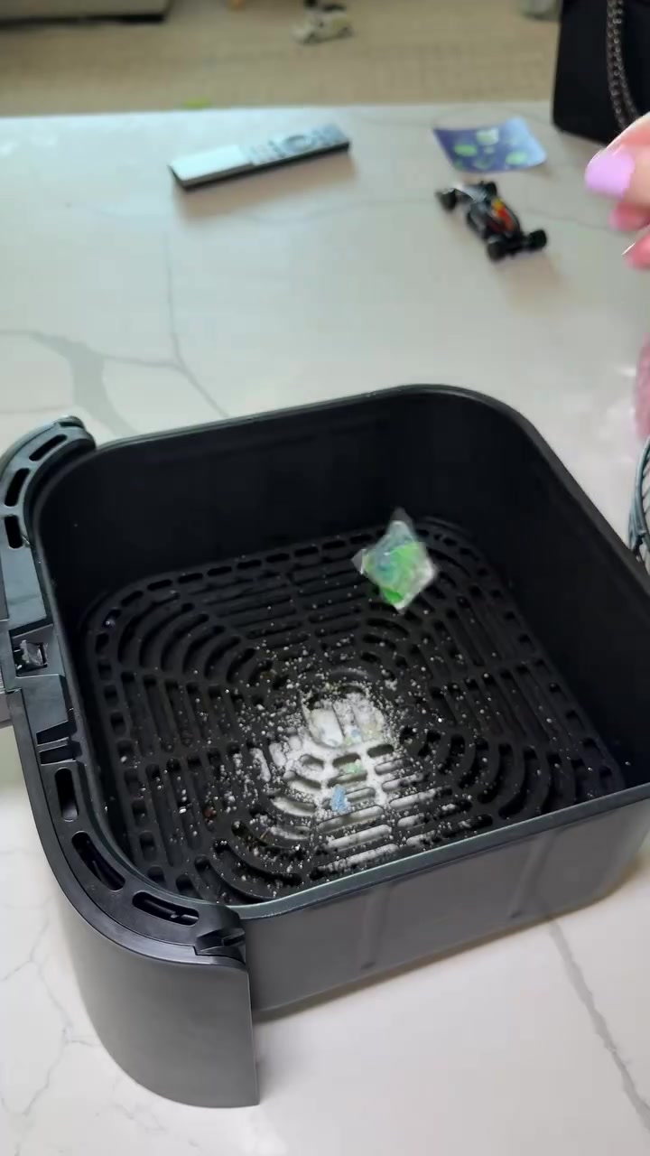 Serbuk baking soda ditabur atas gril basket air fryer yang berkerak minyak