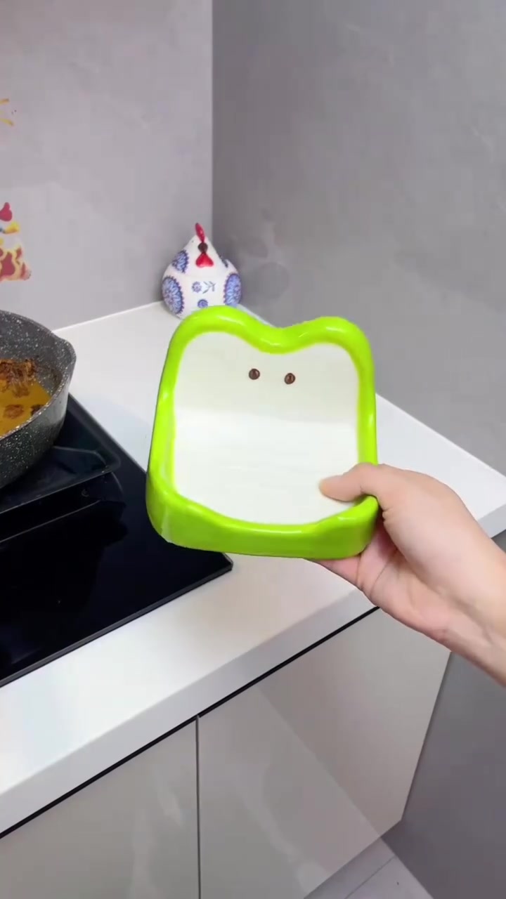 Tangan memegang pemegang kecil berbentuk epal hijau di kaunter berhampiran dapur