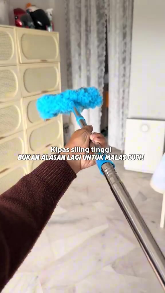 Kepala duster mikrofiber biru dan sambungan batang teleskopik dipegang tangan