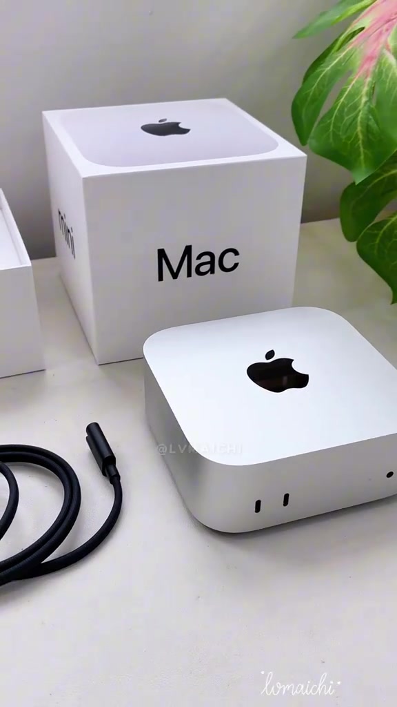 Mac mini màu bạc đặt trước hộp máy, dây nguồn cuộn bên cạnh