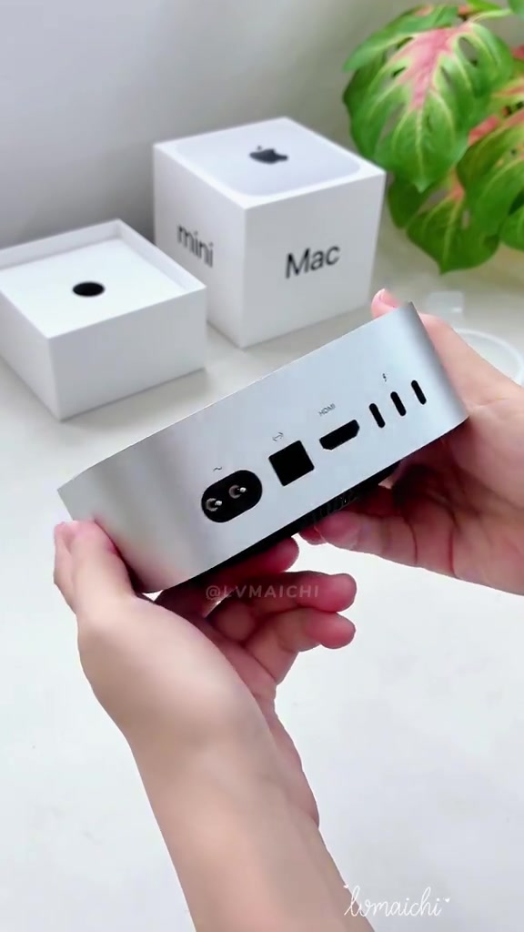 Mặt sau Mac mini được cầm lên để quan sát các cổng kết nối