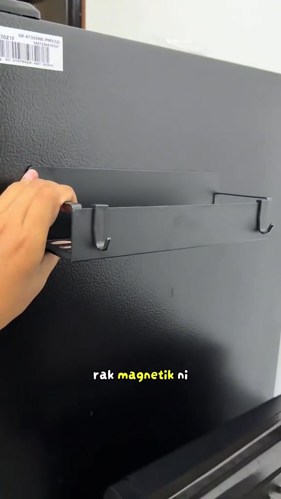Rak magnet bercangkuk dipasang pada sisi peti sejuk hitam.