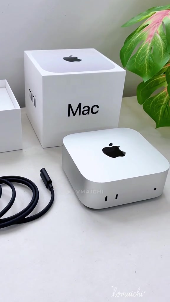 Mac mini màu bạc đặt cạnh dây nguồn và hộp máy trên bàn