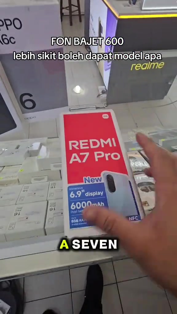 Telefon dan kotak merah Redmi A7 Pro dipamerkan di atas kaunter kedai.