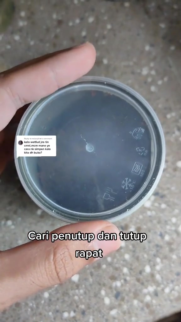 Tangan memegang penutup bulat untuk tin makanan kucing