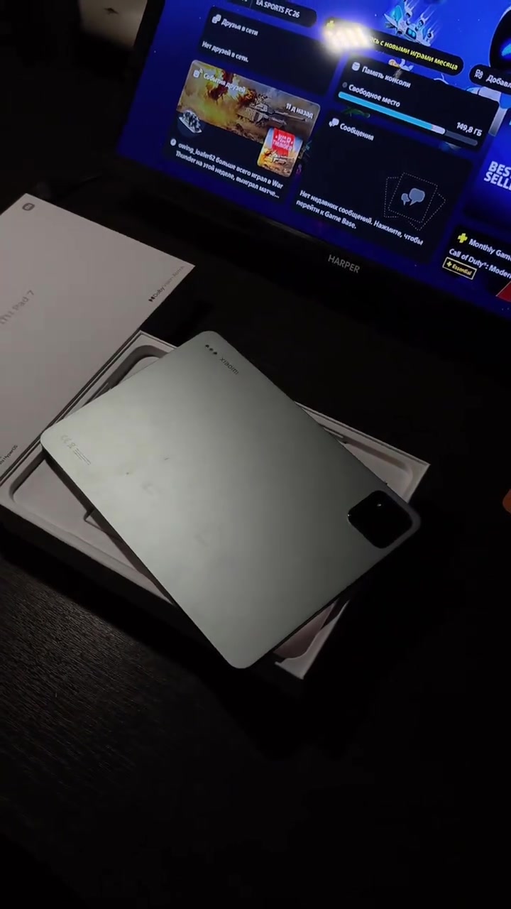 Bahagian belakang Xiaomi Pad 7 di atas kotak, dengan paparan tablet menyala di latar belakang