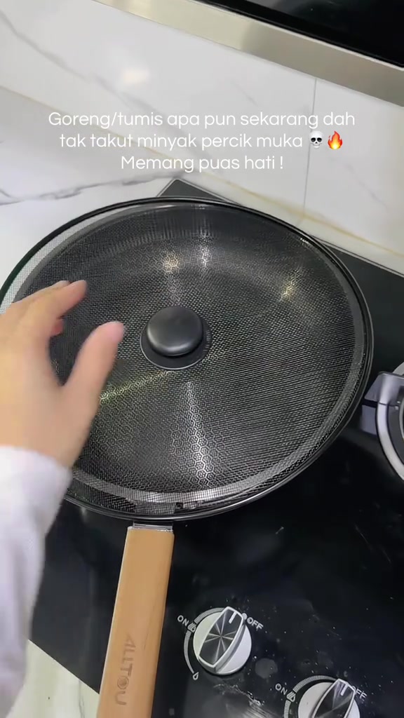 Penutup jaring bulat diletakkan di atas kuali, dengan tangan memegang bahagian pemegangnya.