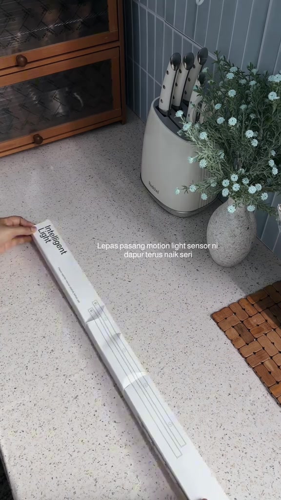 Tangan memegang bar lampu putih panjang di atas kaunter dapur