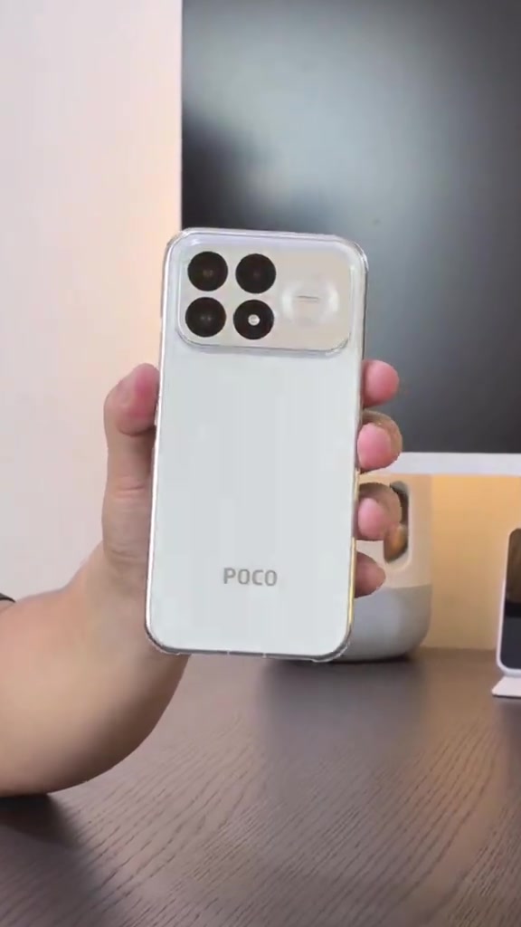 Telefon POCO F9 Pro warna putih dipegang di hadapan meja kerja