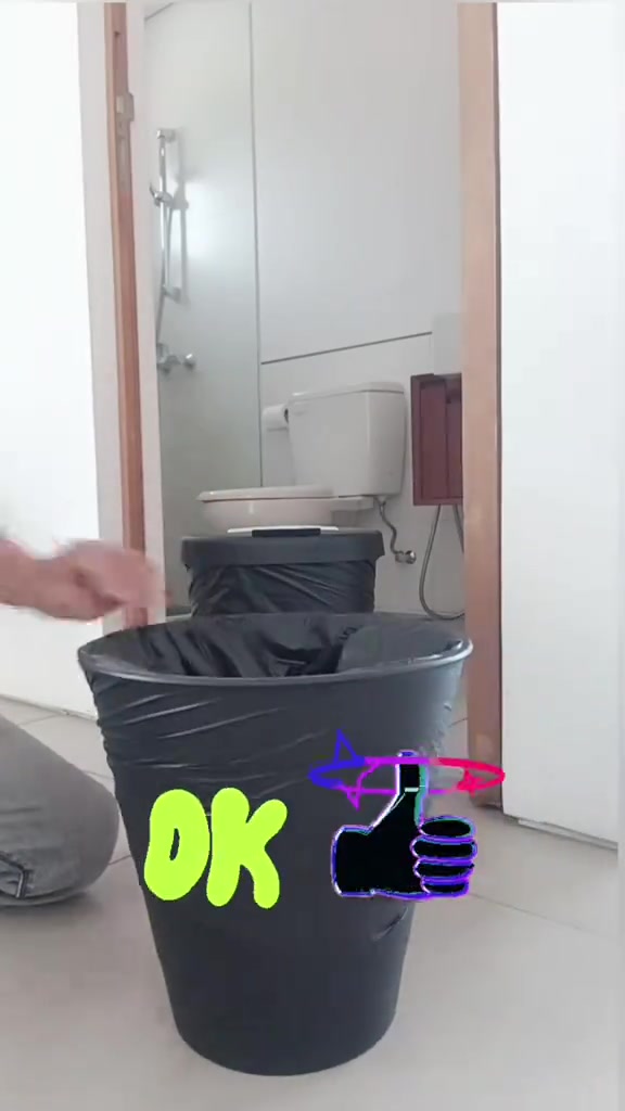 Tangan merapikan beg sampah hitam pada bibir tong biru