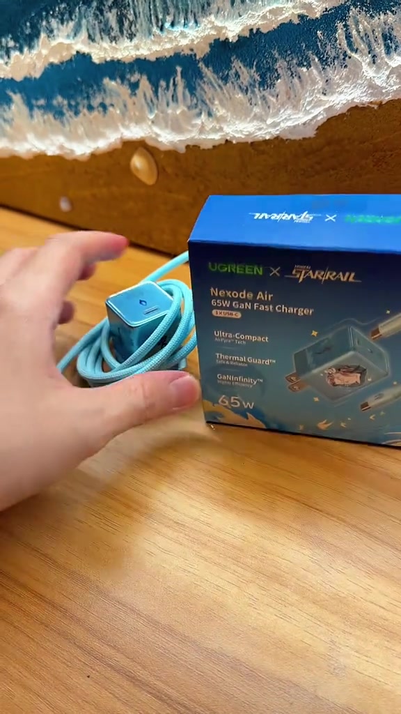Pengecas UGREEN Nexode Air Honkai Star Rail bersama kabel dan kotaknya di atas meja kayu