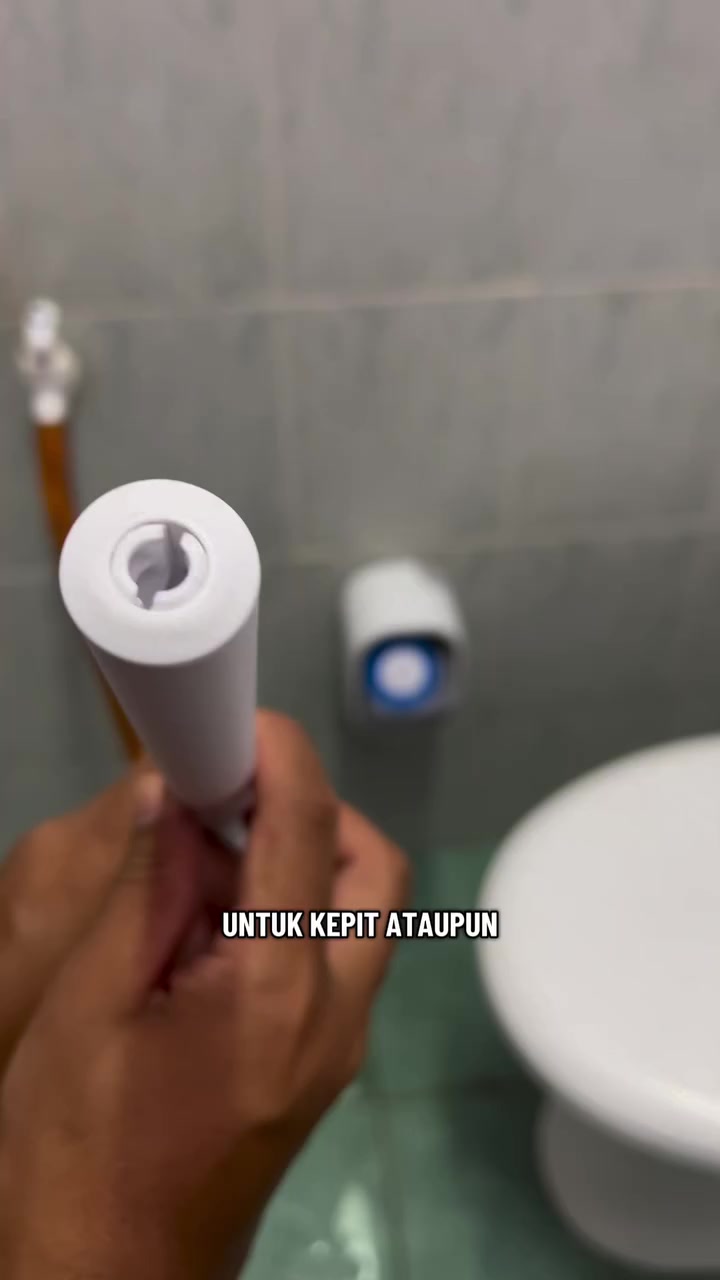 Tangan memegang pemegang berus tandas putih di sisi mangkuk tandas