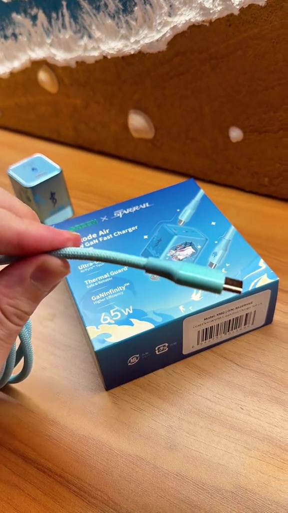 Kabel USB-C braided berwarna cyan di hadapan kotak pengecas Nexode Air