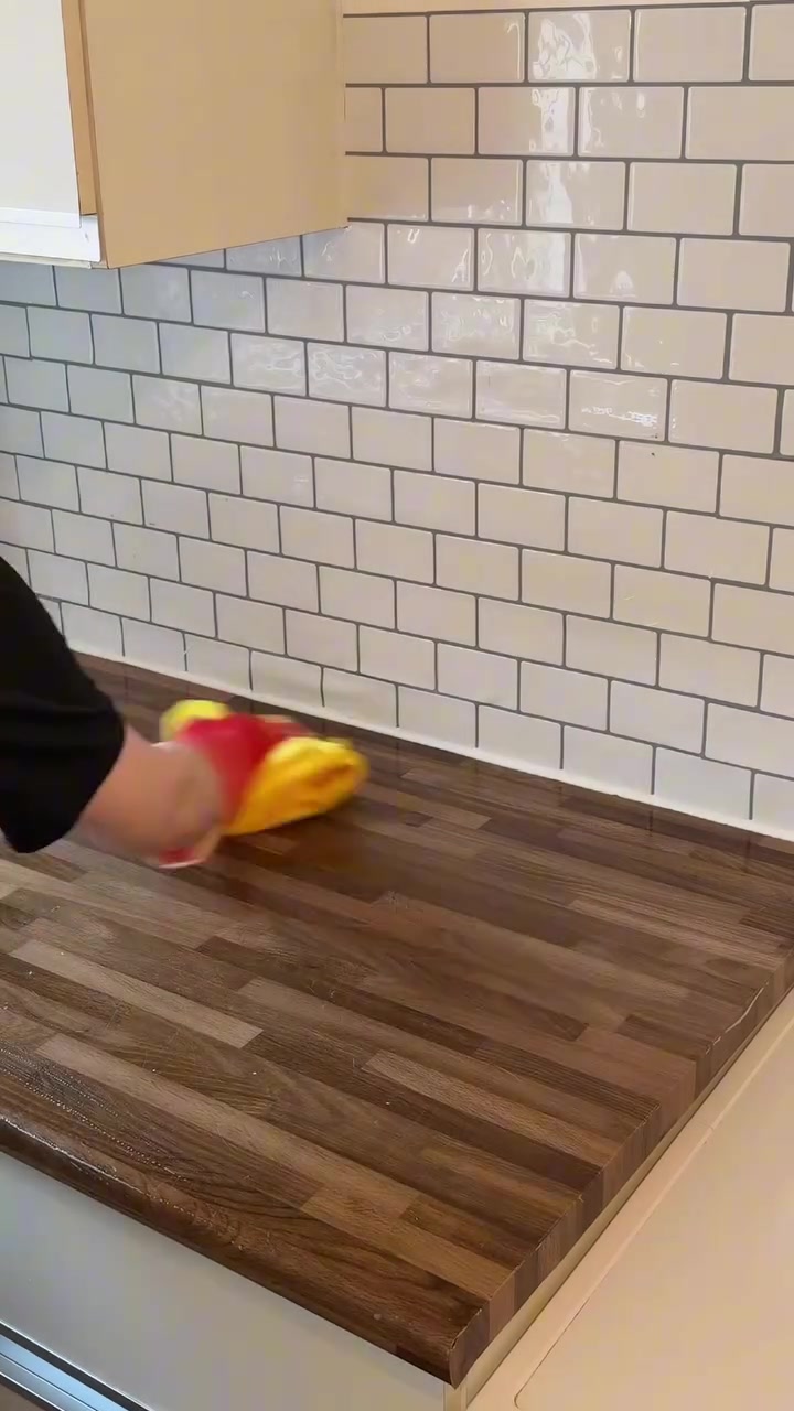 Tangan mengelap permukaan kaunter kayu dengan kain kuning