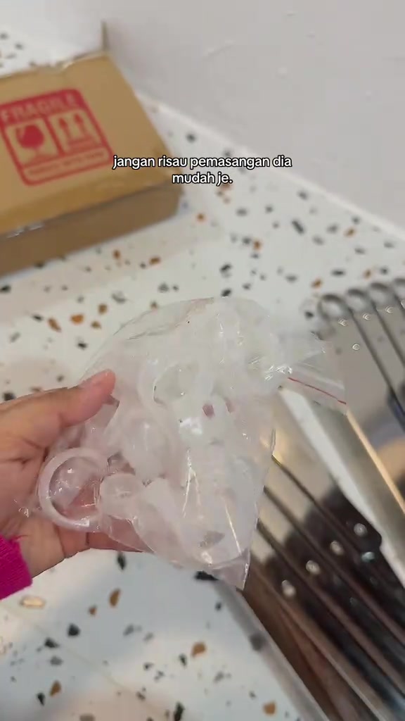 Tangan memegang komponen ampaian dinding dengan beberapa batang rel di lantai sebelum pemasangan