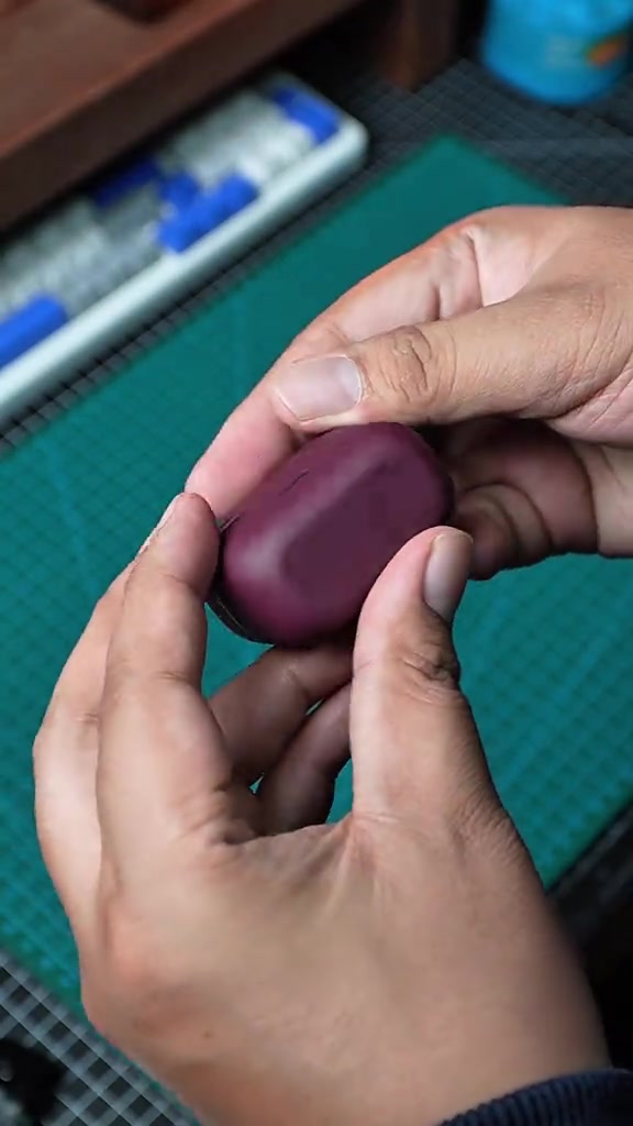 Kes pengecas Soundcore AeroClip 2 warna merah wain dipegang dengan kedua-dua tangan.