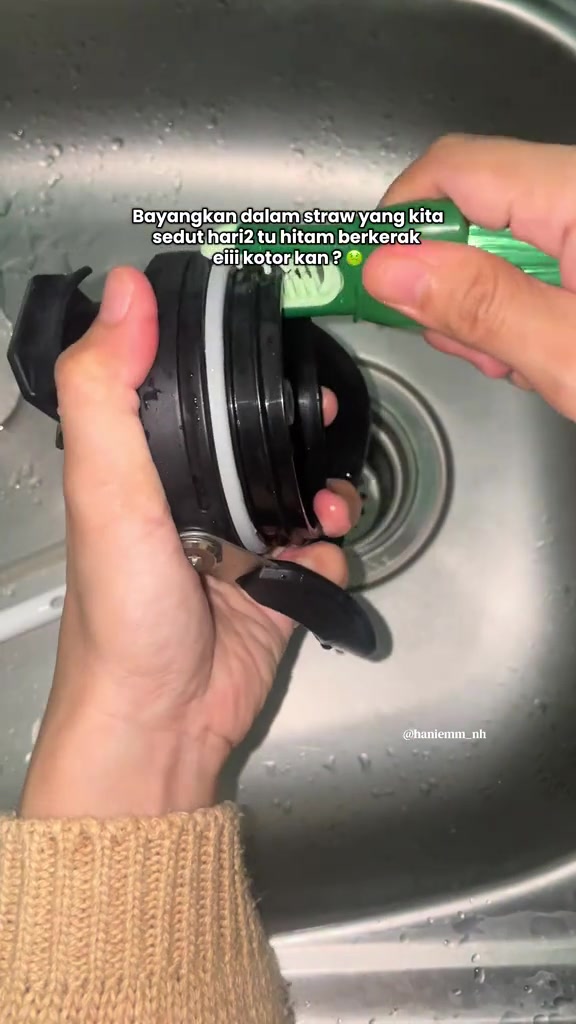 手持小刷清理黑色 tumbler 杯盖的吸管开口