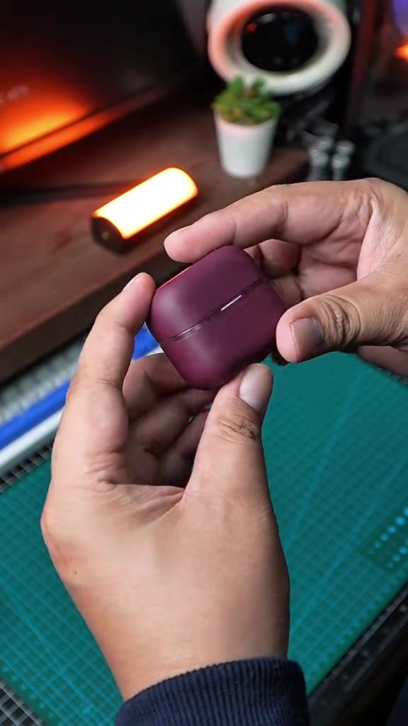 Charging case AeroClip 2 warna burgundy dipegang dengan tangan