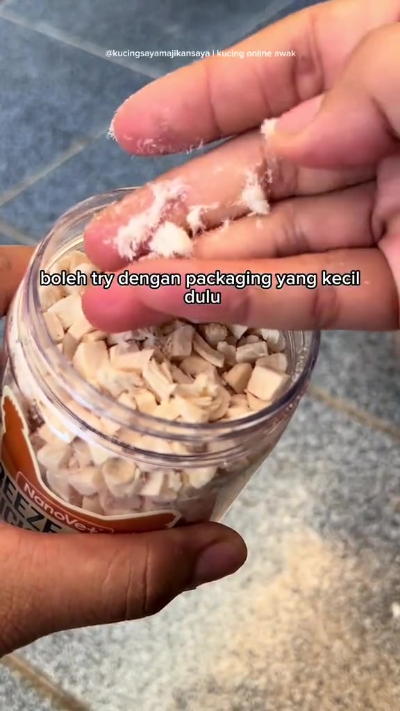 Ketulan salmon kering beku kecil pada hujung jari di atas balang terbuka.
